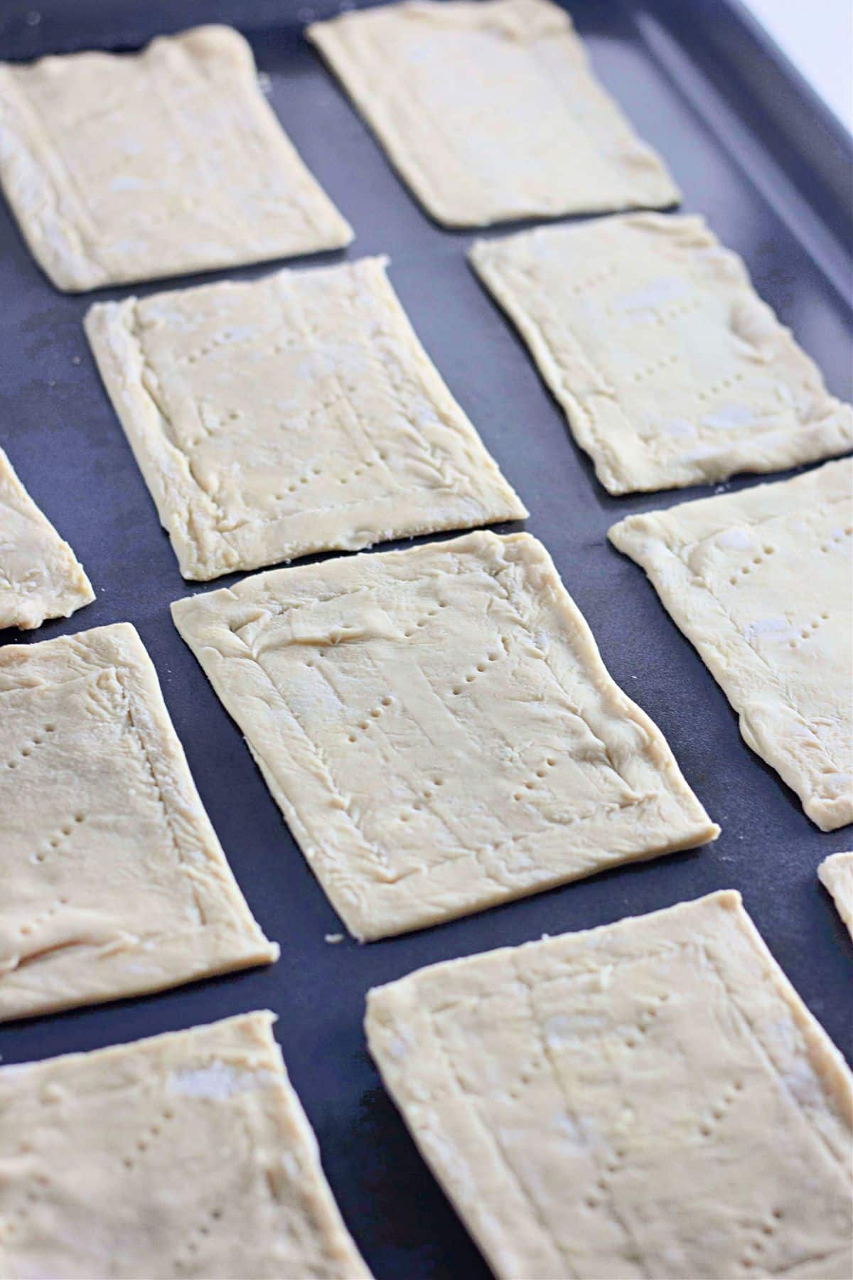 Rectangular pieces of raw pastry dough on a baking sheet, ready to be baked.