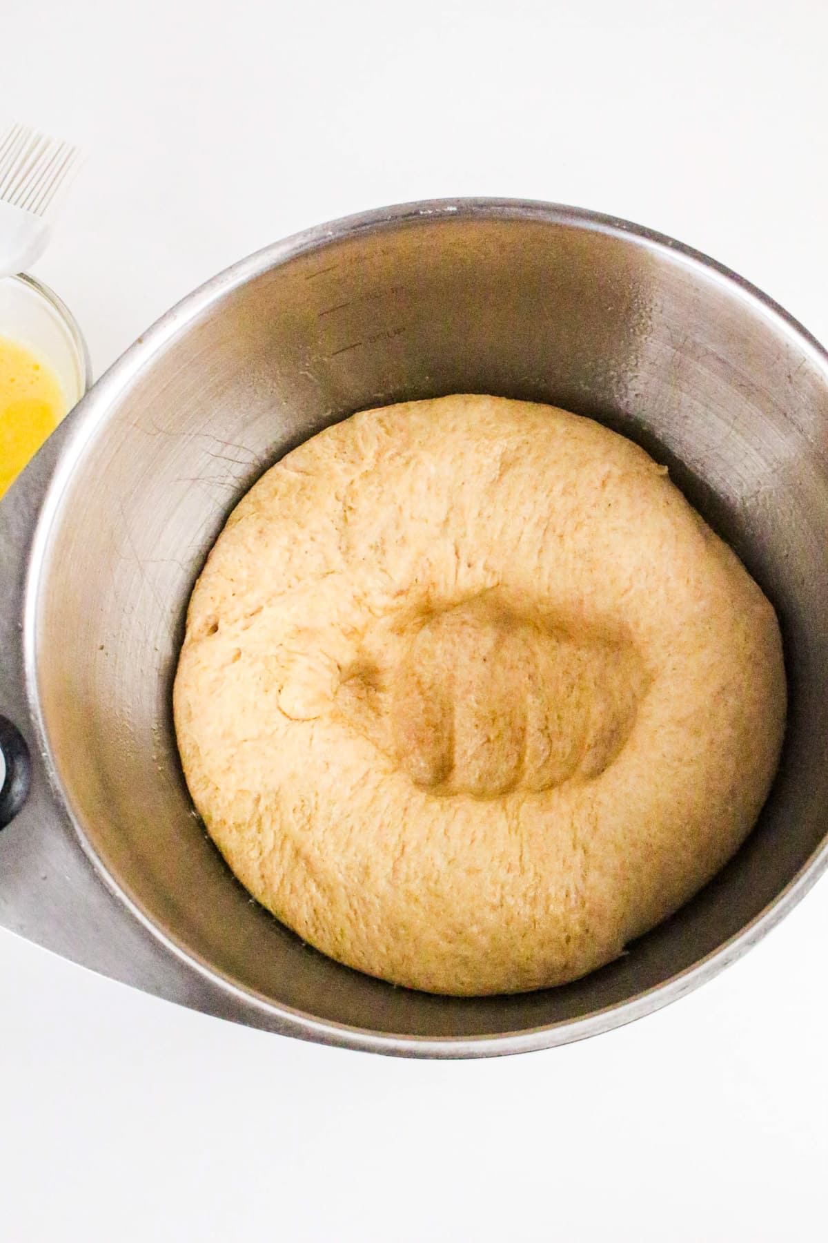 A bowl of risen bread dough with a handprint indentation in the center.