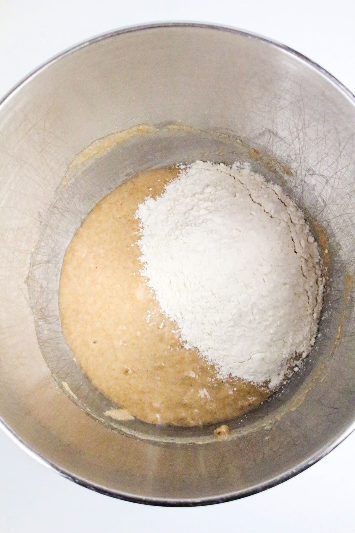 Bowl with dough mixture and a mound of flour on top, ready to be mixed.