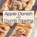 Apple Danish pastries topped with crumb topping and icing are beautifully displayed on a baking tray.