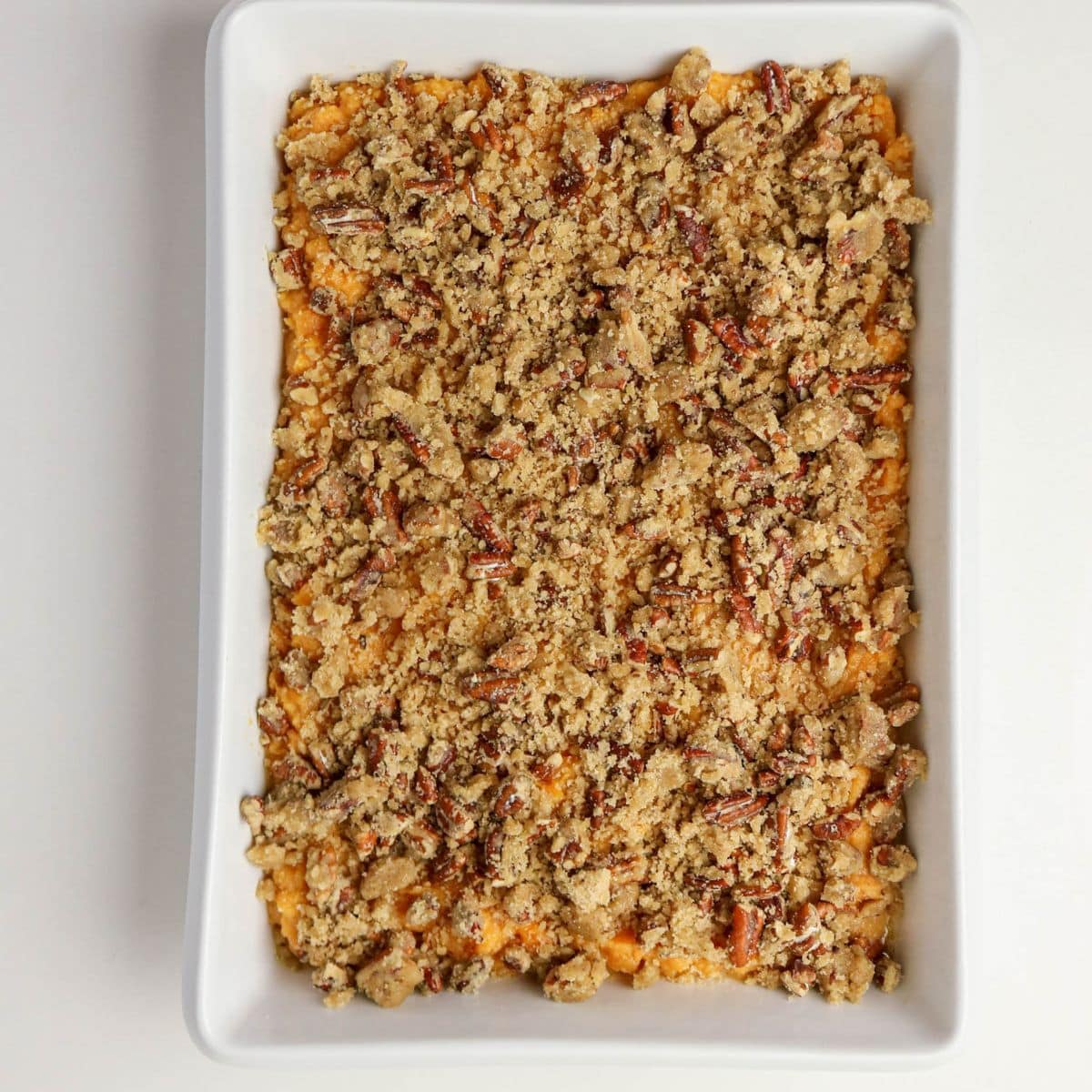 Rectangular baking dish with sweet potato casserole topped with a crumbly pecan streusel.