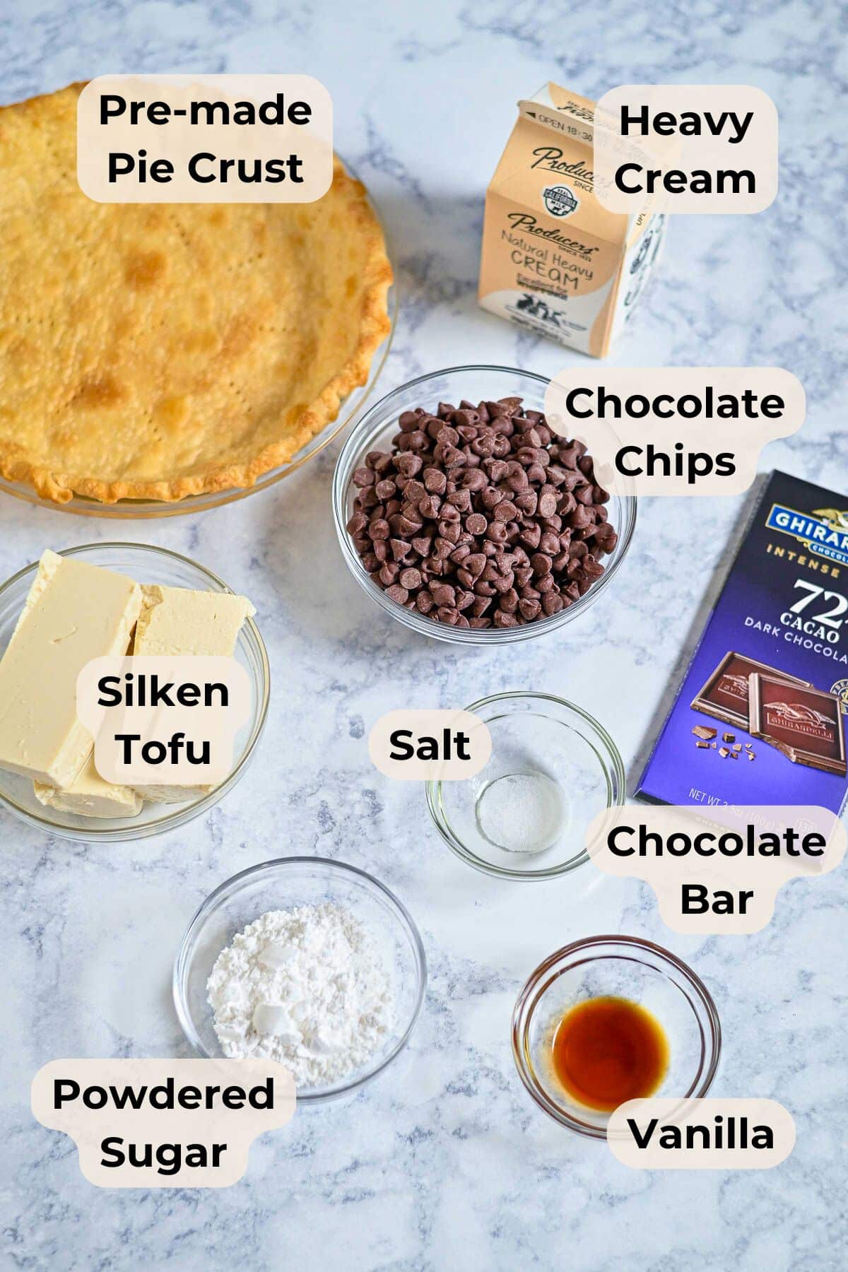 Top-down view of labeled ingredients for a chocolate pie: pie crust, chocolate, tofu, cream, sugar, salt, and vanilla.