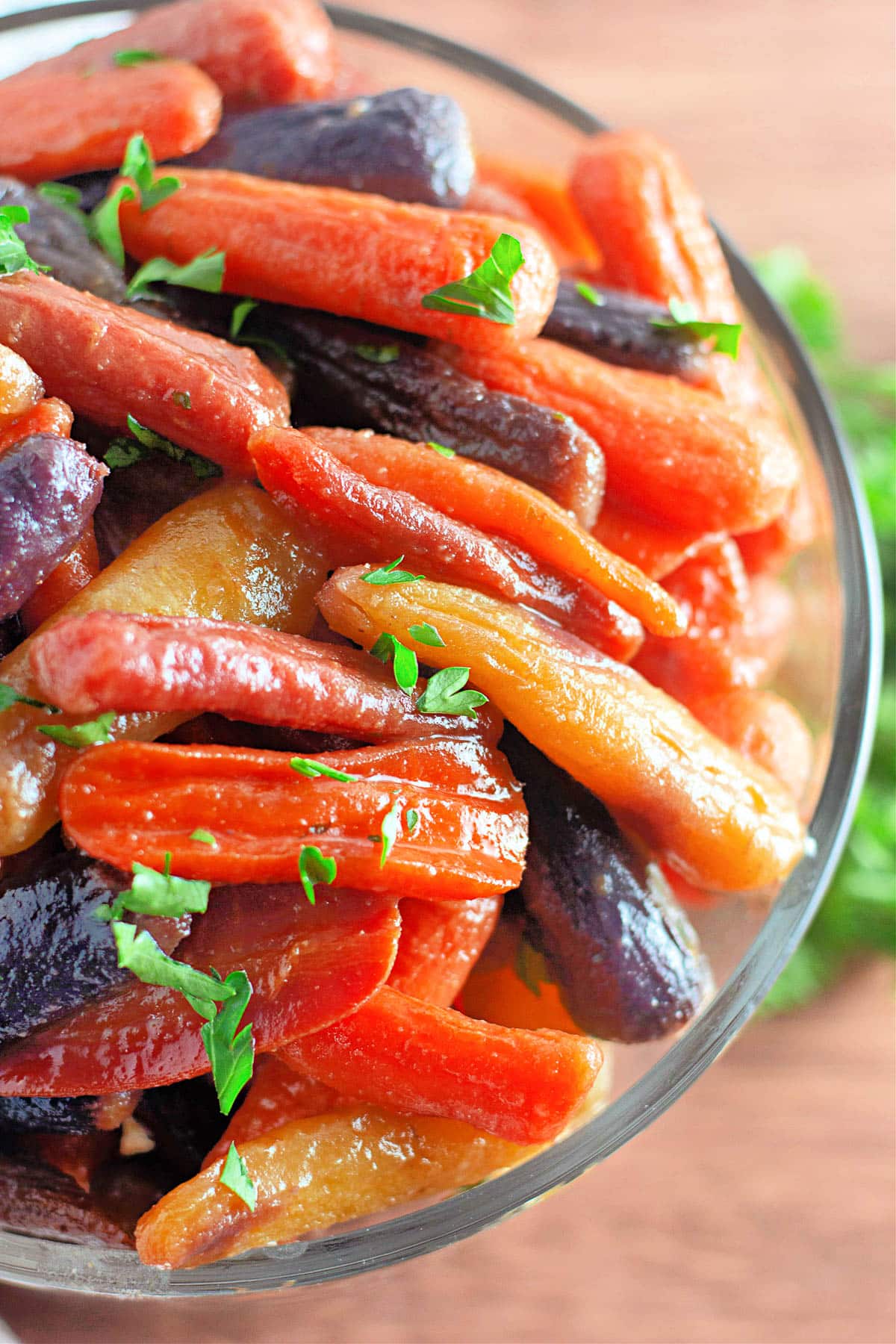 A bowl of roasted rainbow carrots garnished with chopped parsley.