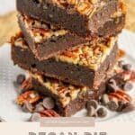 A stack of three Pecan Pie Brownies sits on a white plate, with pecans and chocolate chips scattered around.