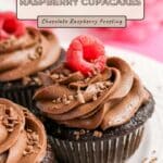 Chocolate Raspberry Cupcakes topped with chocolate raspberry frosting, garnished with fresh raspberries and chocolate shavings.