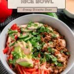 A bowl with ground turkey, sliced avocado, carrots, red peppers, cilantro, and creamy sriracha sauce—these Ground Turkey Rice Bowls are perfect for a fresh and flavorful meal.