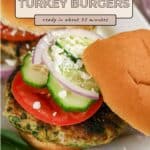 Close-up of Spinach and Feta Turkey Burgers topped with tomato, cucumber, onion, and extra feta on soft buns.