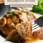 A fork holds a bite of Ground Turkey Salisbury Steak, perfectly smothered in savory mushroom onion gravy on a plate.