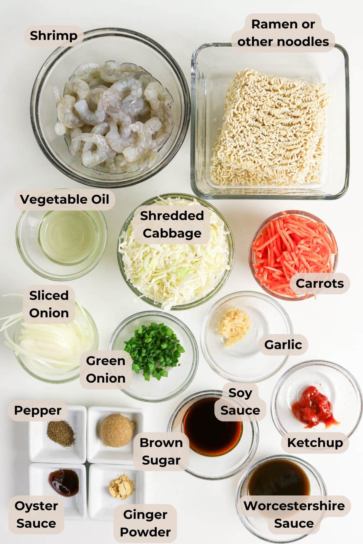 Ingredients for a noodle dish, including shrimp, ramen, vegetables, sauces, and seasonings displayed in bowls.