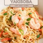 Bowl of shrimp yakisoba with ramen noodles, sliced green onions, and carrots.