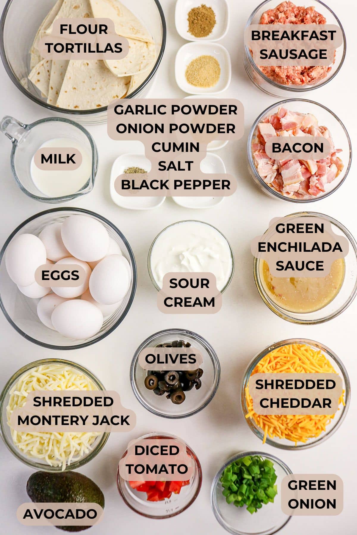 Ingredients for breakfast casserole in bowls: eggs, bacon, sausage, tortillas, cheese, sauces, spices, veggies.