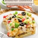 A slice of enchilada breakfast casserole topped with avocado, olives, tomatoes, and green onions on a plate.