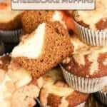 A basket of Pumpkin Cheesecake Muffins, one cut in half to reveal its creamy filling, sits invitingly on a wooden surface.