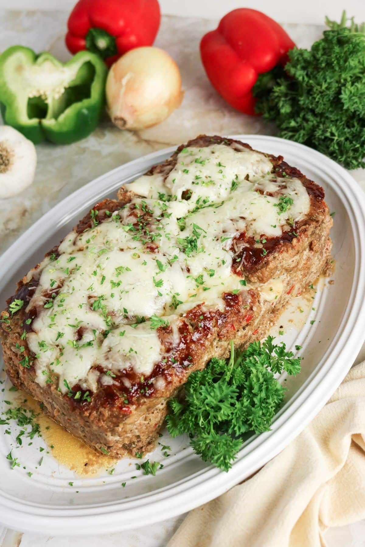 Meatloaf topped with melted cheese and parsley on an oval serving platter.