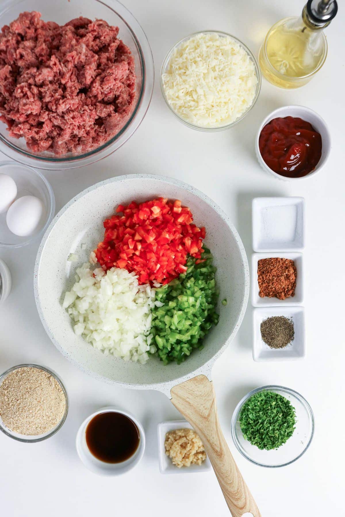 A skillet with diced onions, red peppers, and green peppers surrounded by bowls of ingredients for cooking.