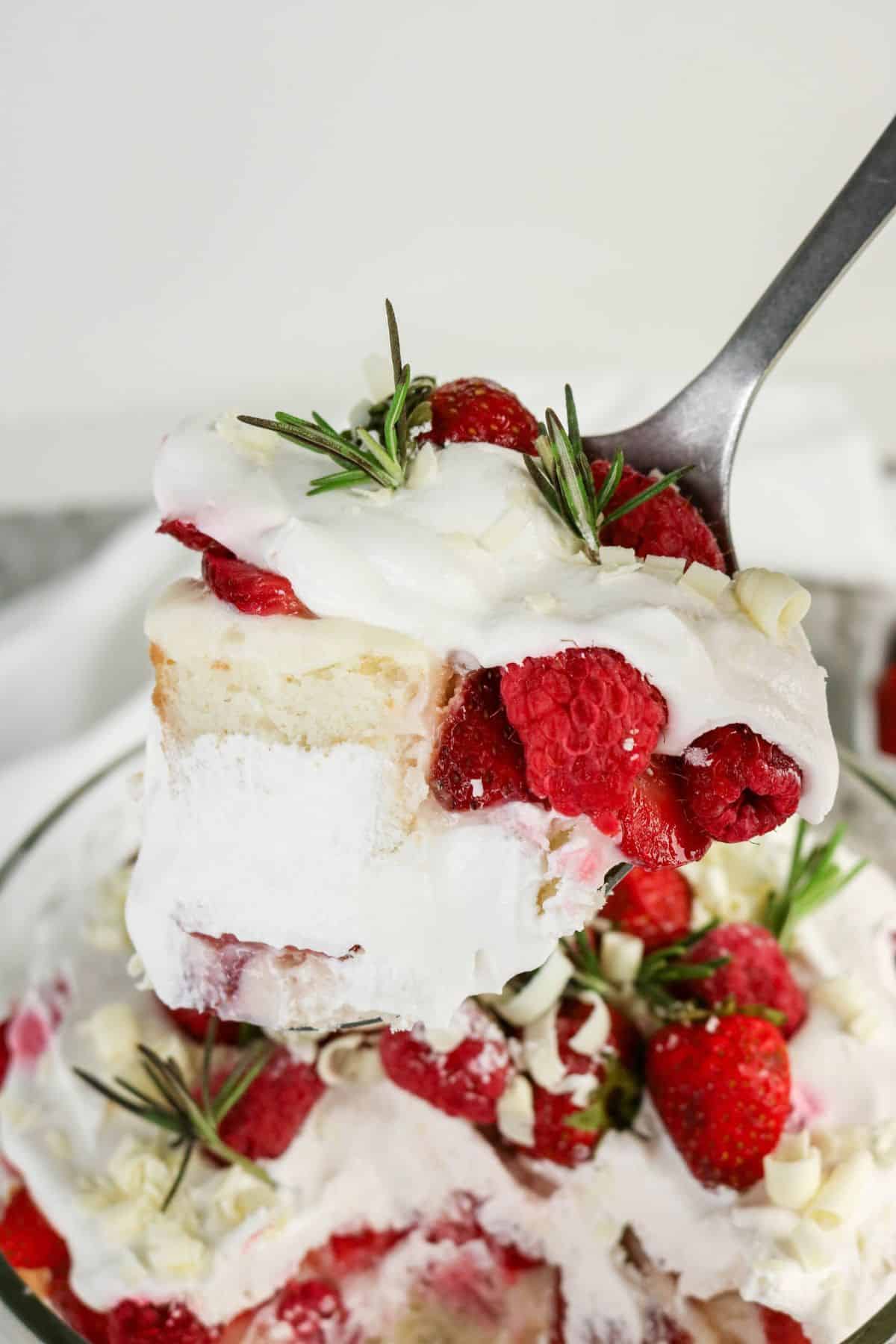 A spoonful of trifle lifted from the bowl, with cake soaked through by the pudding and whipped topping.