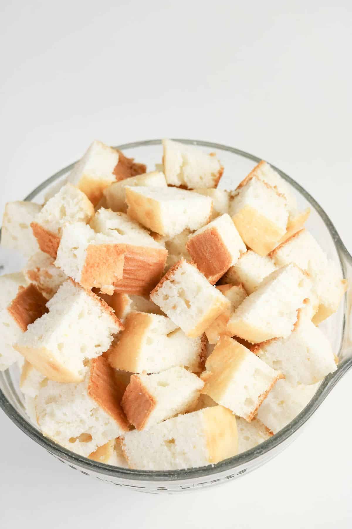 Baked white cake cut into 1-inch cubes in a glass bowl.